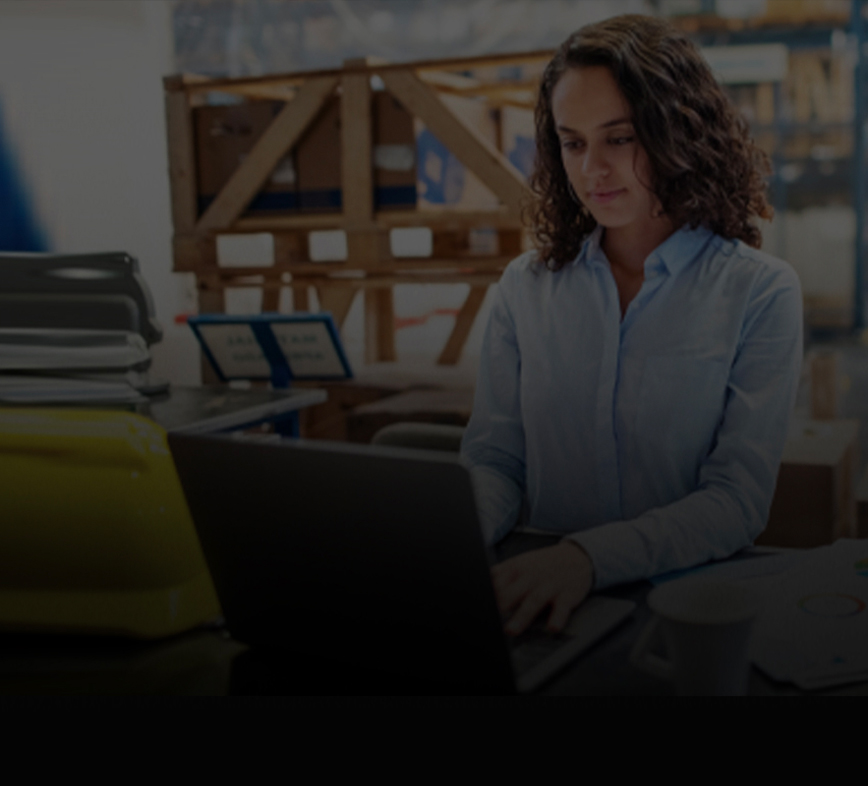 woman typing on a laptop in warehouse