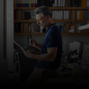 Image of a man tasking off his glasses to read a paper closely